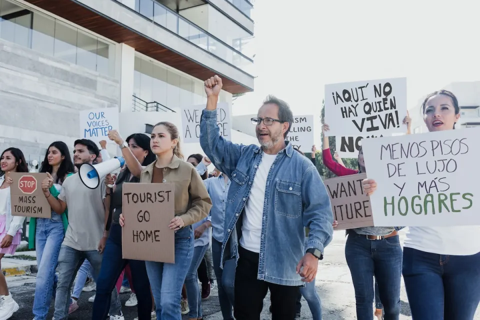 Group of anti-gentrification protesters holding signs like "Tourist go home" in Mexico City.